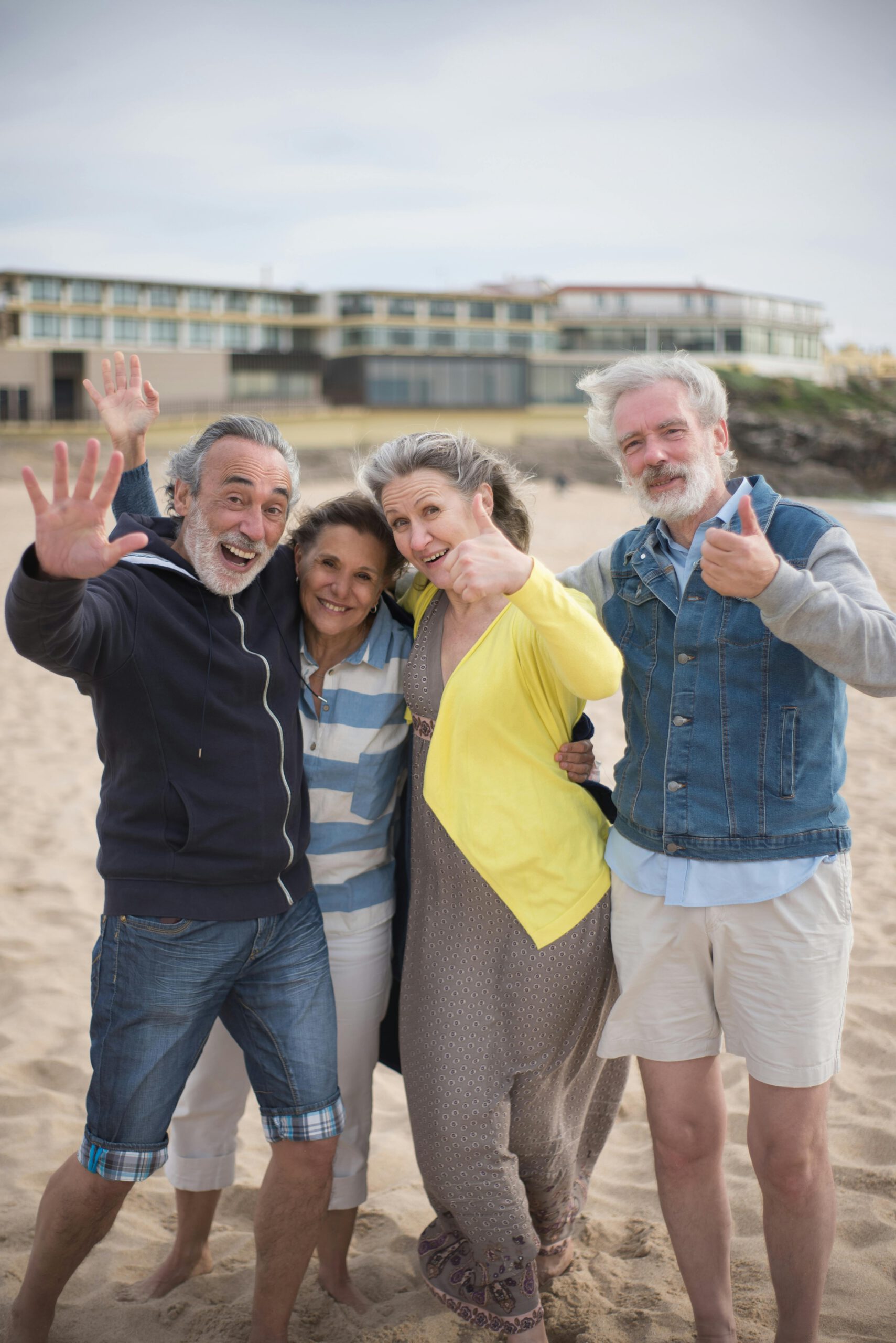 Group of joyful senior friends posing on a sunny beach in Portugal, capturing happy vacation memories together.